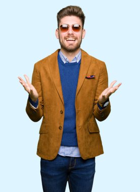 Genç yakışıklı zarif adam deli kutluyor ve silah ile başarı için heyecanlı çığlık kaldırdı ve açık gözleri hayret güneş gözlüğü takıyor. Kazanan kavramı