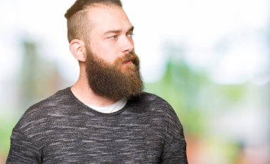 Genç Sarışın giyen sıradan kazak uzak tarafına gülümseme ile yüzünde, doğal ifade arayan adam. Kendine güvenen gülüyor.