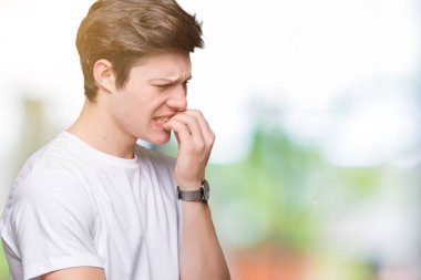 Genç yakışıklı adam stresli ve gergin ile izole arka plan üzerinde rahat beyaz t-shirt giyen tırnak ısırma dudaklarından eller. Anksiyete sorunu.