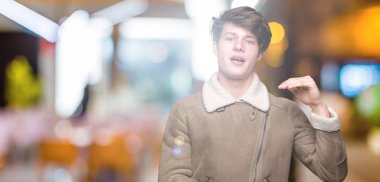 Genç yakışıklı adam büyük ve büyük boy işareti gösteren elleri ile izole arka plan gesturing üzerinde kış ceket giyen, sembol ölçmek. Kameraya bakarak gülümsüyor. Ölçme kavramı.