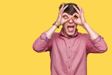 Genç yakışıklı iş adamı, dilini parmaklarının arasından baktığını yapışmasını dürbün gibi ok jest yapıyor izole arka plan üzerinde. Deli ifade.