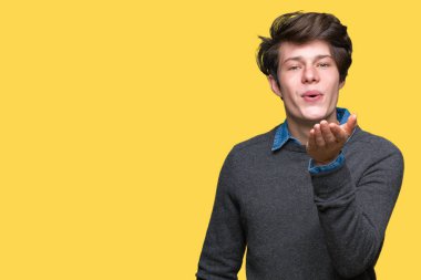 Genç yakışıklı zarif adam izole arka plan bir öpücük el ile güzel ve seksi olmak hava üfleme kamera bakıyor. Aşk ifade.