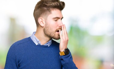 Genç yakışıklı bussines adam esneme yorgun kapsayan ağız el ile sıkılmış. Restless ve uyku hali.