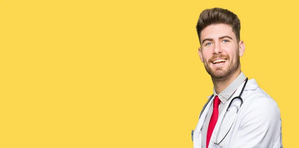 若いハンサムな医者の男の身に着けている医療の手側にポインティングをコートし 広告笑顔幸せと自信を持って提示 手のひらを開く — ストック写真