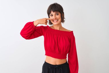 Kırmızı yazlık tişört giyen genç güzel kadın izole beyaz arka plan üzerinde duran yüz ve burun el parmağı ile işaret, neşeli gülümseyen. Güzellik konsepti