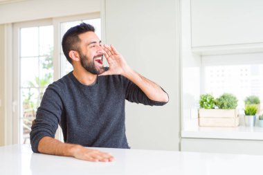 Yakışıklı, İspanyol bir adam evde günlük süveter giyip el ele tutuşarak bağırıyor ve çığlık atıyordu. İletişim konsepti.