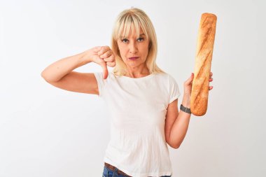 Orta yaş fırıncı kadın kızgın yüz ile izole beyaz arka plan üzerinde duran ekmek tutan, başparmak aşağı, ret kavramı ile sevmediğimi gösteren negatif işareti