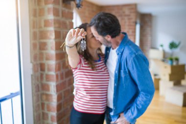 Orta yaş Senior romantik çift Holding ve yeni bir eve taşımak için mutlu gülümseyen ev anahtarlarını gösteren