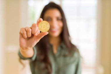 Elektronik ödeme olarak Bitcoin cryptocurrency tutan gülümseyen genç kadın