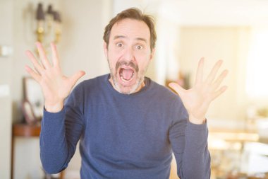 Yakışıklı orta yaş adam evde deli ve başarı için hayran kaldırdı Kollarını açarak kutluyor ve heyecanlı çığlık gözleri açık. Kazanan kavramı