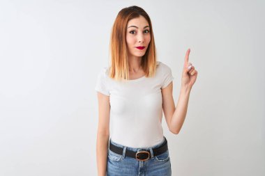 Rahat beyaz arka plan üzerinde duran rahat t-shirt giyen güzel kızıl saçlı kadın gösteren ve kendinden emin ve mutlu gülümserken parmak sayısı bir işaret.