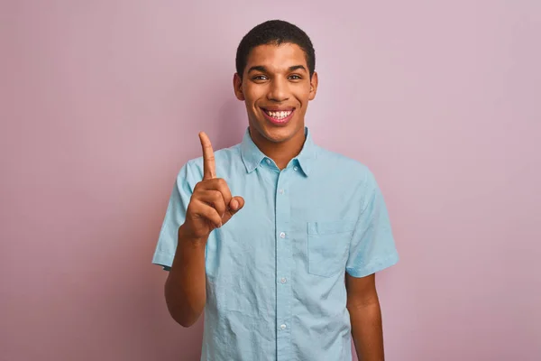 年轻英俊的阿拉伯男子 身穿蓝色衬衫 站在孤立的粉色背景上 带着第一指尖 面带微笑 自信而快乐 — 图库照片