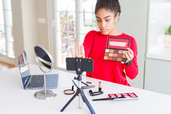 Young african american influencer woman recording make up tutorial with open hand doing stop sign with serious and confident expression, defense gesture