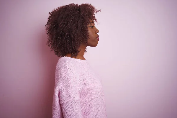 年轻的非洲非洲裔妇女穿着毛衣站在孤立的粉红色背景寻找一边 放松配置文件姿势与自然的脸与自信的笑容 — 图库照片