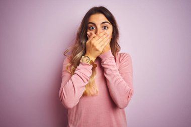 Genç güzel kadın pembe izole arka plan üzerinde bir kazak giyen hata için elleri ile ağız kapsayan şok. Gizli kavram.