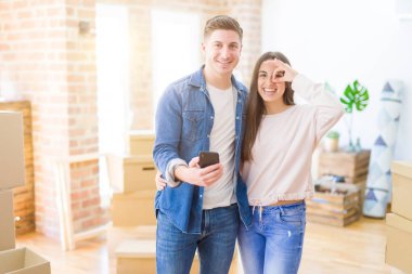 Mutlu yüzü ile yeni bir eve hareket eden güzel genç çift parmakları ile bakarak göz üzerinde el ile ok işareti yapıyor gülümseyerek