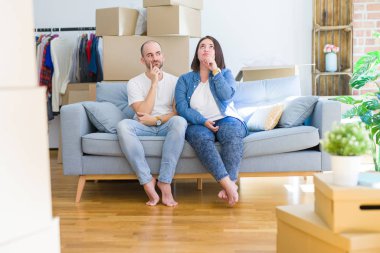 Kanepede oturan genç çift, yeni bir eve hareket eden karton kutularda elleri çenesi üzerinde soru, dalgın ifade yi düşünüyor. Düşünceli bir yüzle gülümsüyor. Şüphe kavramı.