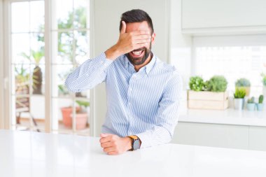 Yakışıklı İspanyol iş adam gülümseyen ve sürpriz için gözleri kapsayan yüzünde el ile gülüyor. Kör kavram.