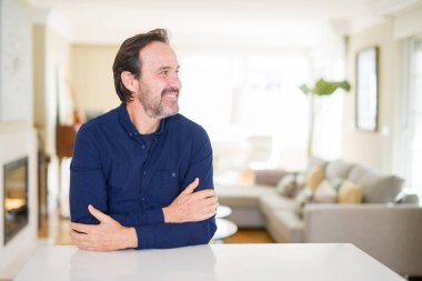 Yakışıklı orta yaş evde uzak tarafına gülümseme ile yüzünde, doğal ifade adamım. Kendine güvenen gülüyor.