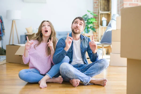 Joven Hermosa Pareja Moviéndose Una Nueva Casa Sentada Suelo Asombrada — Foto de Stock