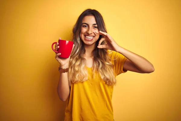 Νεαρή Όμορφη Γυναίκα Κρατώντας Κόκκινο Φλιτζάνι Καφέ Πάνω Από Κίτρινο — Φωτογραφία Αρχείου