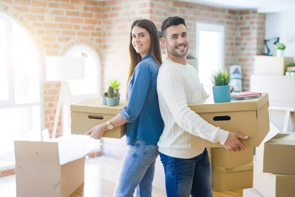 Pareja joven mudándose a un nuevo hogar, sonriendo feliz sosteniendo cardboa —  Fotos de Stock