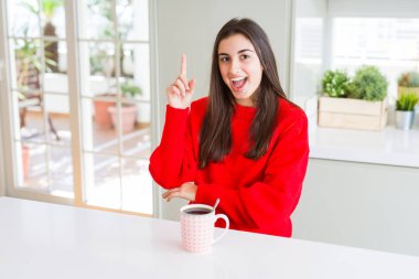 Güzel genç kadın başarılı bir fikir ile parmak işaret siyah kahve bir fincan içme. Çıktı ve mutlu. Bir numara.
