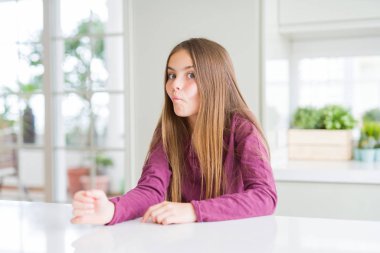 Dudakları, çılgın ve komik jest ile balık yüz yapma beyaz masada güzel genç kız çocuk. Komik ifade.