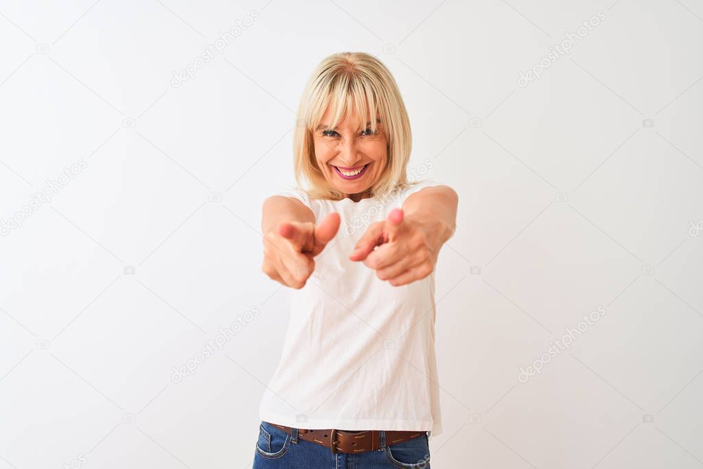 Middle age woman wearing casual t-shirt standing over isolated white background pointing to you and the camera with fingers, smiling positive and cheerful