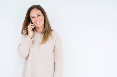 Akıllı telefondan konuşan orta yaşlı bir kadın mutlu bir yüzle ayakta duruyor ve gülümsüyor dişlerini gösteren bir gülümsemeyle.