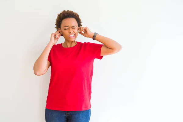 白い背景の上の若い美しいアフリカ系アメリカ人女性は 大音量の音楽の騒音のためにいらいらした表情で耳を覆っています ろうの概念 — ストック写真