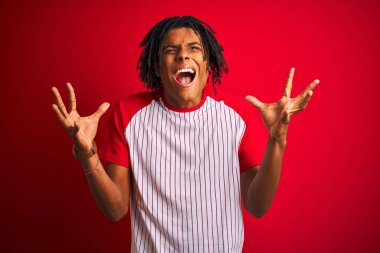 Dreadlocks çizgili t-shirt giyen Afro adam izole kırmızı arka plan üzerinde ayakta silah kaldırdı ve kapalı gözleri ile başarı için deli ve deli kutluyor heyecanlı çığlık. Kazanan kavramı