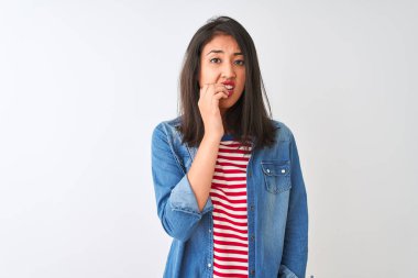 İzole edilmiş beyaz arka plan üzerinde çizgili t-shirt ve kot gömlek giyen genç Çinli kadın elleri ağız yiyen tırnaklarla stresli ve gergin görünüyor. Endişe sorunu.