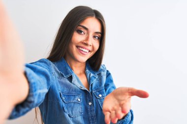 Kot gömlek giyen güzel bir kadın izole edilmiş beyaz arka planda fotoğraf çektirirken mutlu bir gülümsemeyle avuç içi yardım ve kabullenme sunuyor..