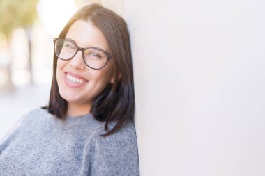 Gözlüklü neşeli duvarda, kasaba, casual güzel kız eğilerek gülümseyen güzel genç kadın