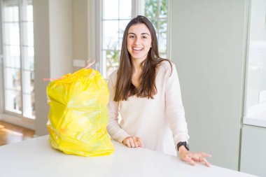 Güzel genç kadın yüzünde mutlu ve serin bir gülümseme ile çöp konteyner çöp çıkararak. Şanslı kişi.