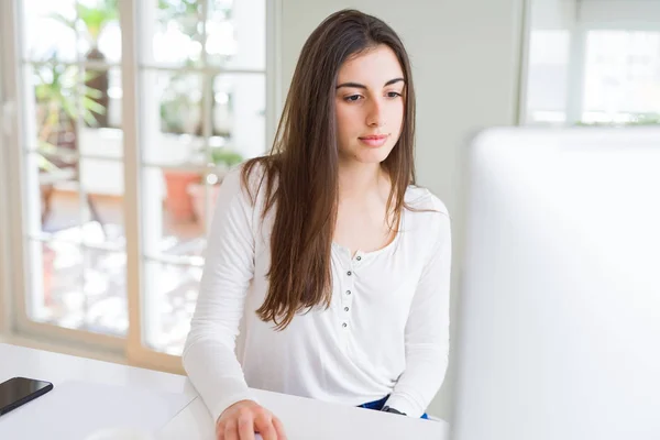 Schöne junge Geschäftsfrau, die mit Computer arbeitet, lächelnd ein — Stockfoto