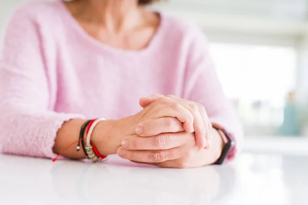 Крупним планом жінка середнього віку схрестила руки над білим столом — стокове фото