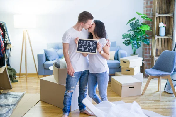 段ボール箱の周りの新しい家でメッセージと黒板を持って床に立つ若い美しいカップル — ストック写真
