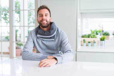Evde rahat sweatshirt giyen ve olumlu gülümseyen yakışıklı adam