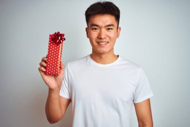 Genç asyalı çinli adam mutlu bir yüz ayakta ve dişleri gösteren kendinden emin bir gülümseme ile gülümseyerek izole beyaz arka plan üzerinde duran sevgililer mevcut tutan