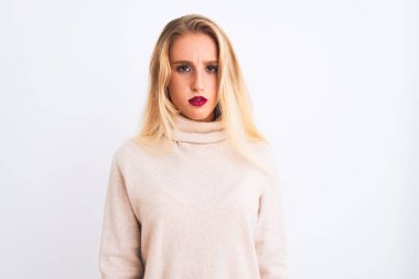 Genç güzel kadın boğazlı kazak giyen izole beyaz arka plan şüpheci ve sinir üzerinde duran, sorun nedeniyle üzgün kaşlarını çatma. Negatif kişi.