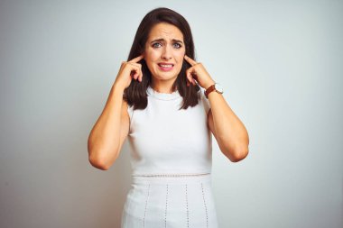 Gürültülü müzik sesi için beyaz izole edilmiş arka planda dikilen elbiseler giyen genç ve güzel bir kadın kulaklarını parmaklarıyla kapatıyor. Sağır kavramı.