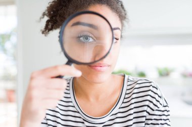 Genç afro-amerikan kadın akıllı yüz ciddi düşünme kendine güvenen bir ifade ile büyüteç ile bakıyor