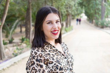 Bahçede mutlu gülümseyen kırmızı dudaklı genç güzel kadın