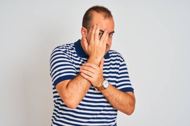 İzole edilmiş beyaz arka planda duran sıradan çizgili polo giyen genç bir adam. Ağlarken suratını ellerle kapatan üzgün bir ifade. Depresyon kavramı.