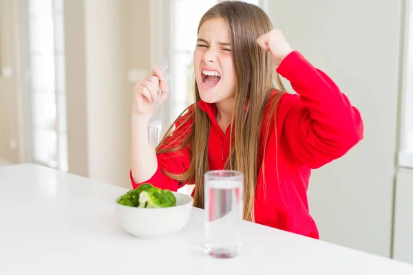 新鮮なブロッコリーと飲料水を食べる美しい若い女の子の子供は怒りで怒り 狂気と叫び声で怒り 怒りの概念で怒りを叫んでイライラしました — ストック写真