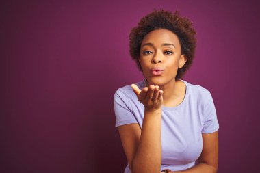 Izole mor arka plan üzerinde afro saçlı genç güzel afro-amerikan kadın hava güzel ve seksi olmak eliyle bir öpücük üfleme kameraya bakıyor. Aşk ifadesi.