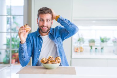 Çikolata lı çörek yiyen yakışıklı adam, eliyle stresli, utanç ve sürpriz yüz, kızgın ve sinirli ile şok. Korku ve hata için üzgün.