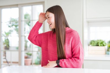 Beyaz masada pembe kazak giyen güzel bir Asyalı kadın çok mutlu ve gülümseyerek başını kaldırıp uzaklara bakıyor. Konsept aranıyor.